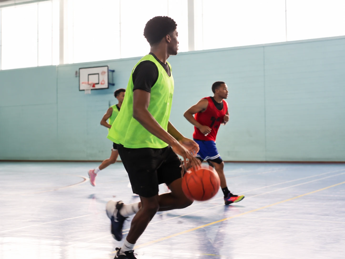 Young players competing in a basketball game inside a school sports hall