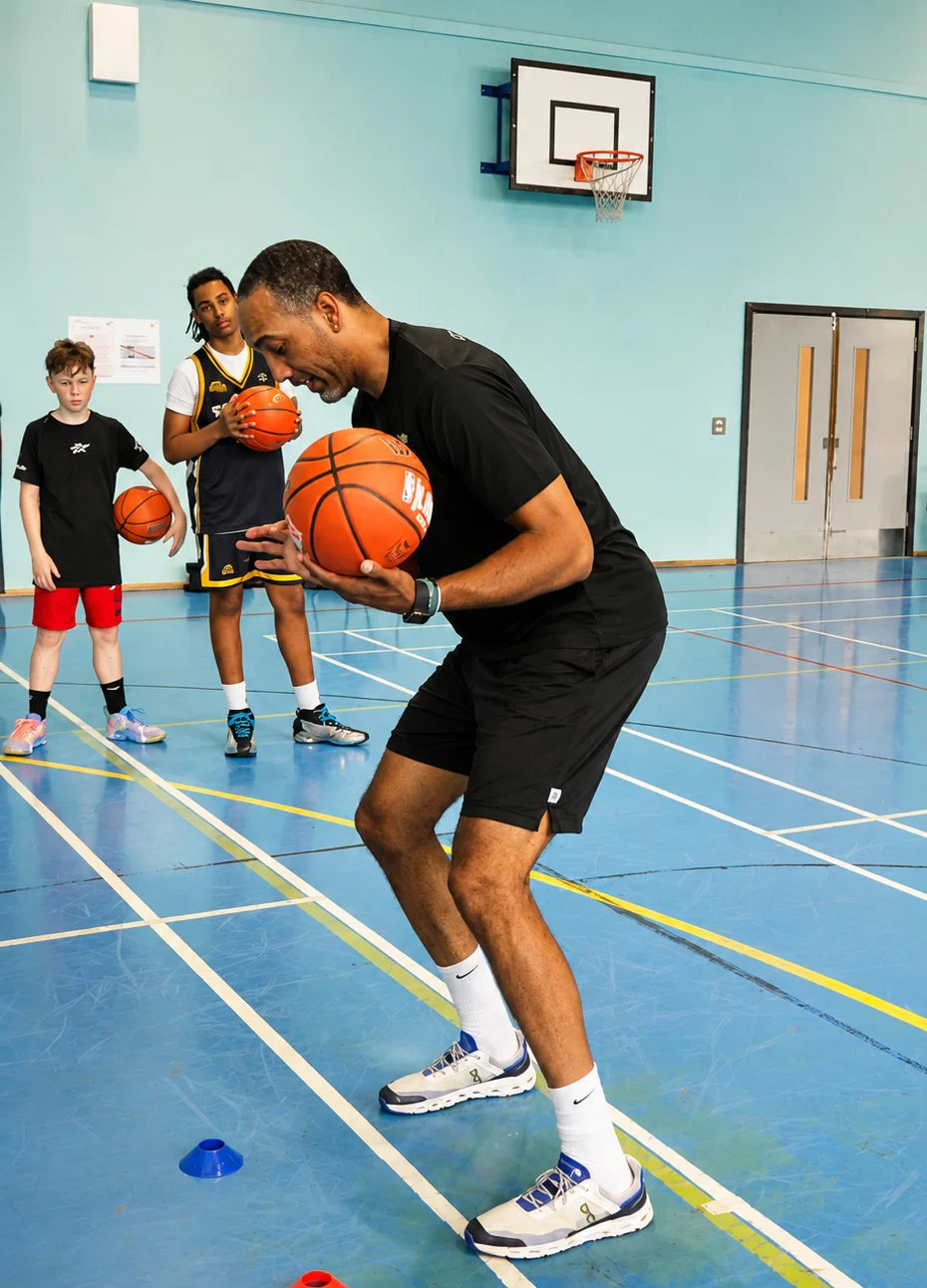 Coach demonstrating ball-control technique to youth camp players