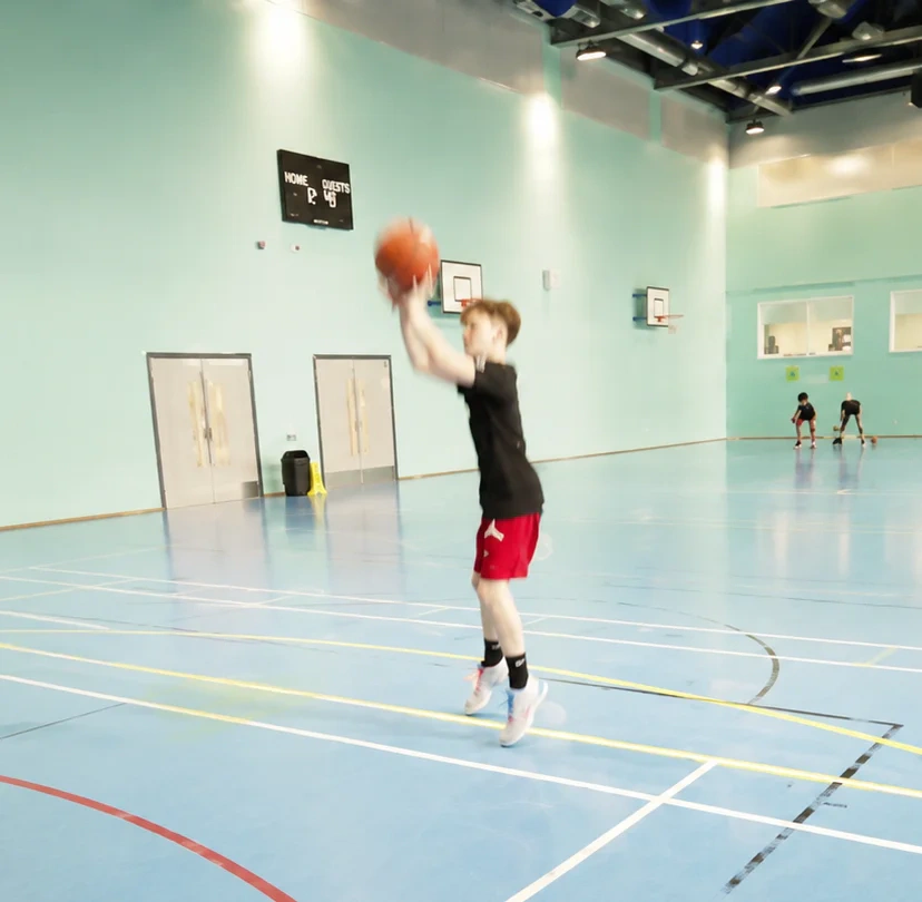 Young basketball player taking a jump shot during youth camp
